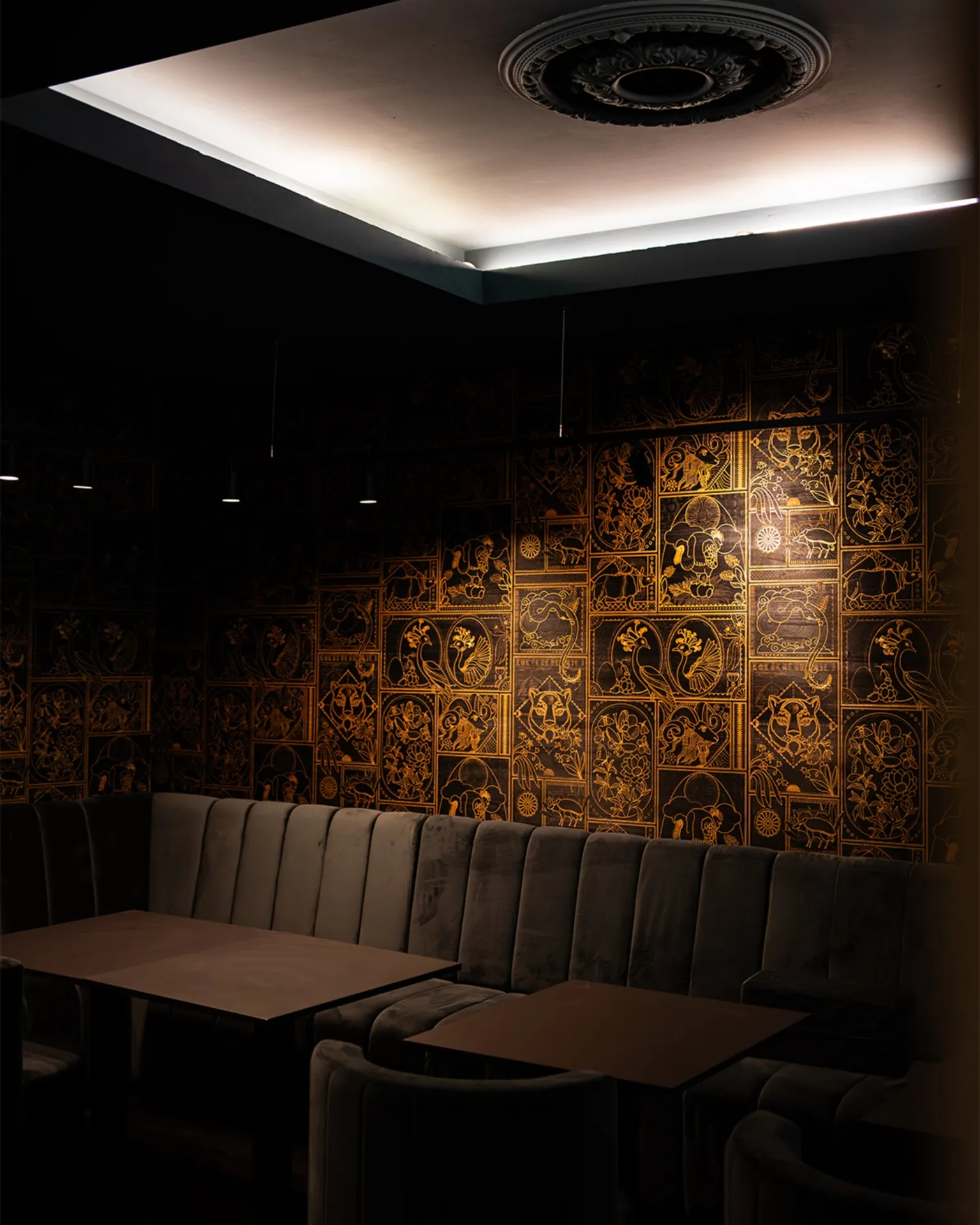Innenraum des Restaurants essence india in Hamburg – Samtbanquette vor der handbemalten goldenen Pichwai-Wand